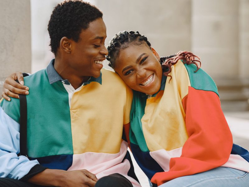 People in identifical clothes. African couple in autumn city. People sitting on a street.